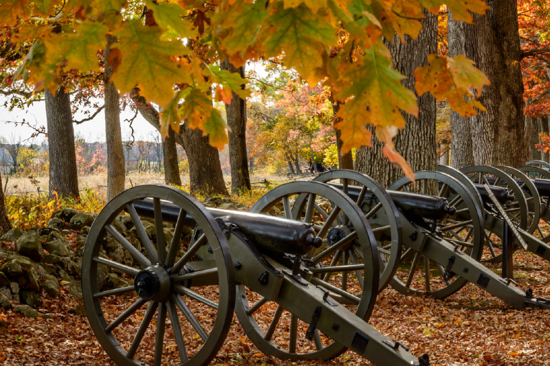 A row of cannons line an autumnal pathway in Gettysburg, PA