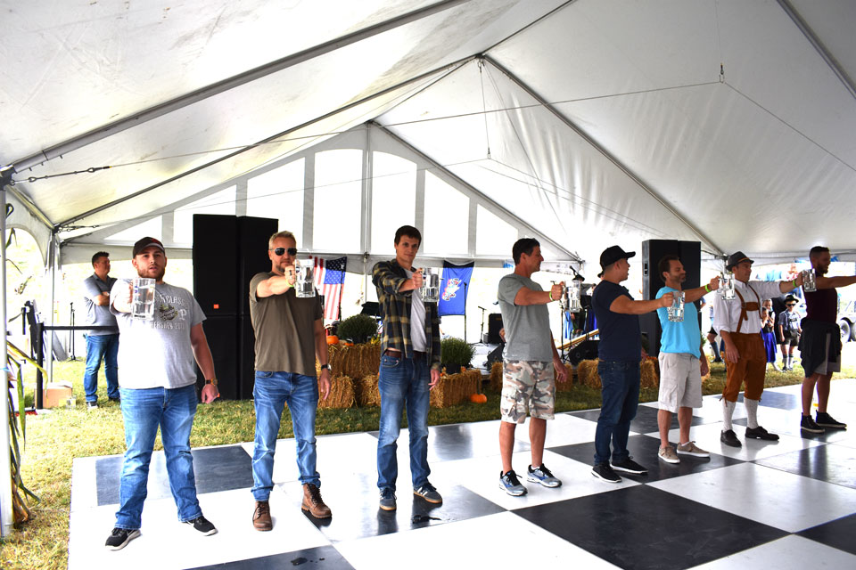 group of men lineup raising hands holding beer mug