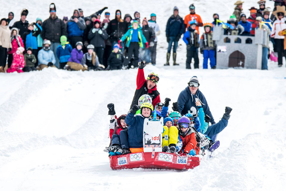 a team with group of kids sliding using a cardboard sled