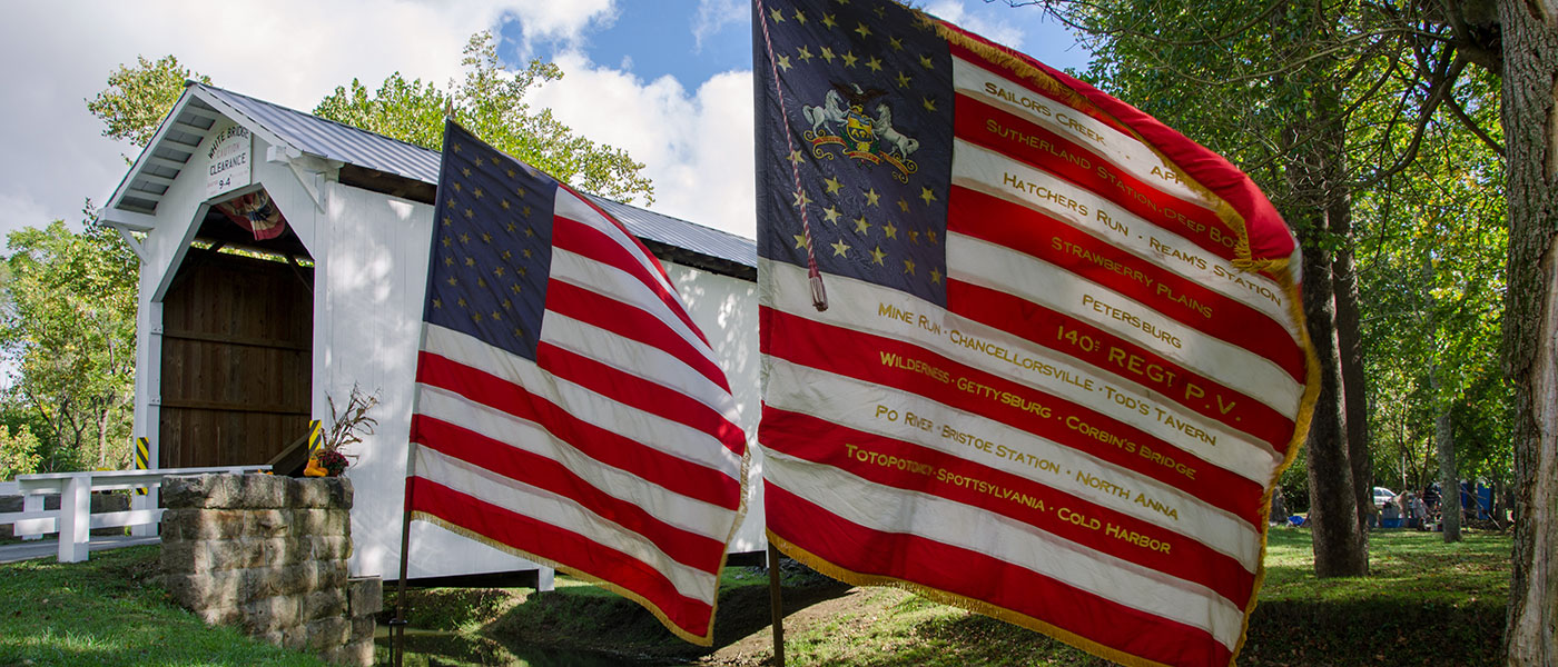 two American flags posted near covered bridge