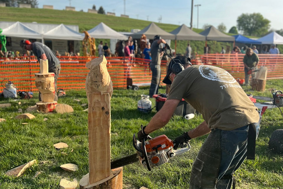 carvers carving wood log using chainsaw