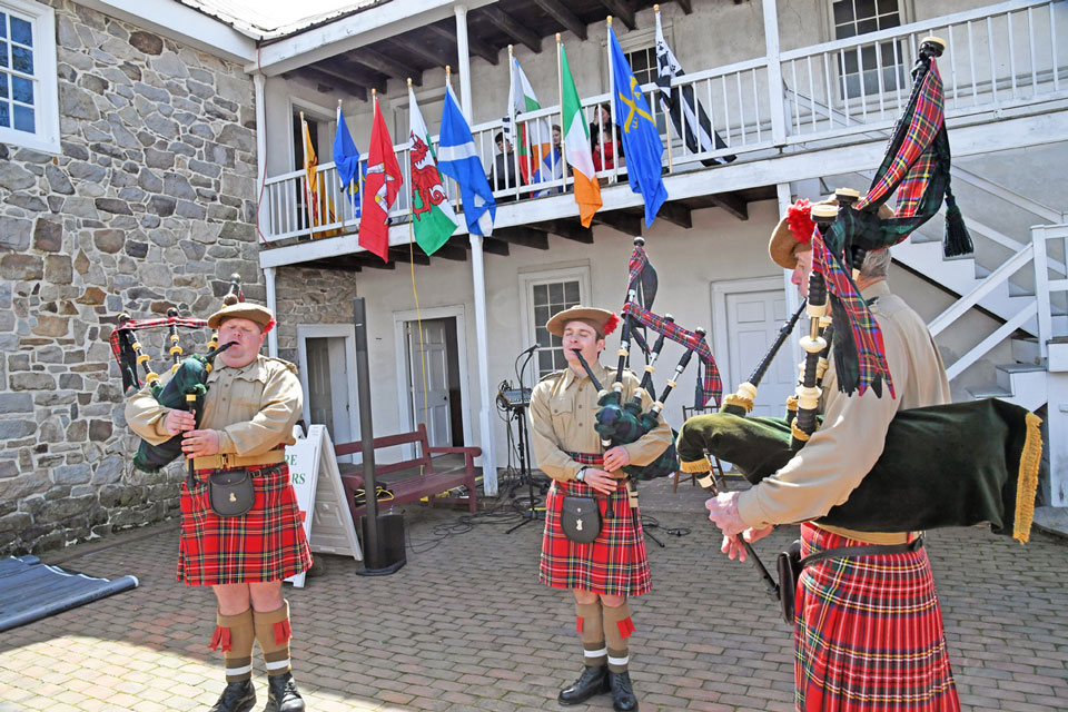 band of three dressed Scottish and playing bagpiper