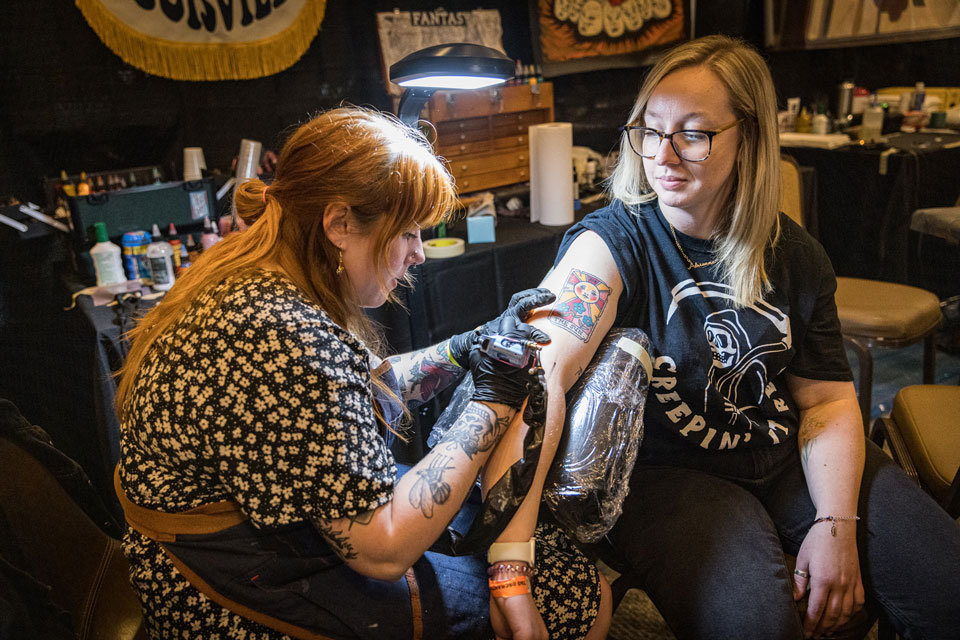 a tattoo artist working on a patron