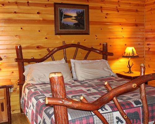 Interior of a log cabin with a wooden bedframe and plaid comforter